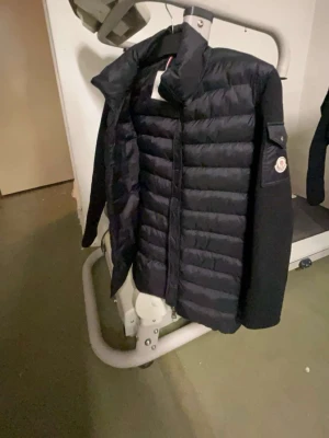 Svart cardigan  - Säljer en svart pufferjacka från Moncler med quiltad front och släta ärmar. Jackan har dragkedja ärmen. Perfekt för dig som vill ha en stilren och varm jacka med snygg passform.