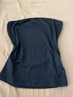 Mörkblå tubtopp från SHEIN - Snygg mörkblå tubtopp från SHEIN i storlek XS. Enkel och stilren design utan axelband, perfekt för att skapa en cool och avslappnad look. Materialet är mjukt och stretchigt syntet som sitter bekvämt mot kroppen. Passar dig som gillar minimalistiska plagg.