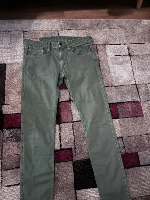 Gröna Replay jeans, modell Waitom - Snygga gröna jeans från Replay, modell Waitom. Klassisk femficksdesign, raka ben och normal passform. Tillverkade i bomull med en skön känsla och diskreta detaljer. Perfekta för dig som vill ha en stilren look med lite edge. Om ni undrar något eller vill ha bättre bild så kontakta mig!