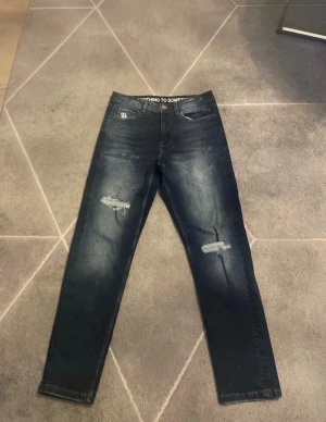  Hoodrich jeans - Snygga mörkblå jeans från Hoodrich. Klassisk femficksmodell med broderad logga på fickan och läderpatch bak i midjan. Jeansen har en fräsch tvätt och är perfekta för en cool streetstil. Aldrig använda dom är helt nya. 28-W, 96cm långa. hör av er vid frågor!