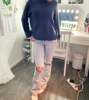 Mörkblå stickad tröja med rund hals - En enkel och snygg mörkblå stickad tröja med rund hals och långa ärmar. Tröjan har en loose passform och ribbade muddar vid hals, ärmslut och nederkant. Perfekt att slänga på sig när det är lite kyligt ute.