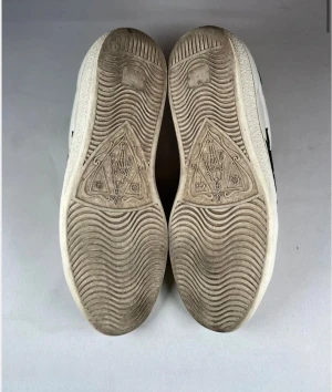 Gucci sneakers Snake - Gucci sneakers i vitt skinn med broderad röd och svart orm på sidan, gröna och röda detaljer samt snörning framtill. Rund tå och platt sula. Bakpartiet har texturerad grön och röd hälflik. Riktigt statement-sneakers för dig som gillar lyx och coola detaljer.