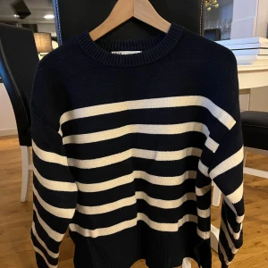 Randig stickad tröja från Zara - Snygg stickad tröja från Zara i marinblått och vitt med klassiska horisontella ränder. Modellen har rund hals, ribbade muddar och lång ärm. Perfekt för dig som gillar en chill och stilren look med lite preppy vibe.