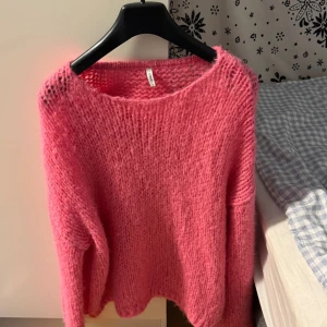 Rosa stickad tröja från ONLY - Mysig rosa stickad tröja från ONLY i storlek S. Tröjan har en lös passform, lång ärm och är gjord i ett fluffigt, grovstickat material som känns både trendigt och bekvämt. Perfekt att slänga på sig när det är kyligt ute.