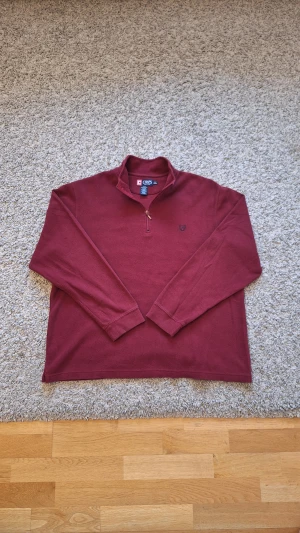 Vinröd half zip stickad tröja från Chaps - Elegant vinröd half zip från CHAPS i storlek XL, men skulle nog säga den passar mer som L. 100% bomull. Använd fåtal gånger och skicket är i princip som ny, inga defekter eller slitningar finns. Den har en halvkrage och halvzipp. Passar perfekt för dig som gillar business casual och vill ha en lite mer elegant stil. Skick: 9/10