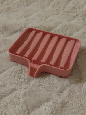 Tvålfat i rosa hård plast - Tvätfat i rosa hårdplast med räfflor. Mått ca l 11cm b 9,5cm h 2,5cm