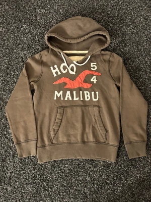 Brun hoodie från Hollister Malibu (sällsynt) - Säljer nu denna sjukt eftertraktade hoodien ifrån hollister. Skick 8/10, Rikigt snygg och passar perfekt nu till hösten. Obs kan gå ner i pris vid snabb affär! Slitage är designen 