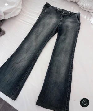 Lågmidjade bootcut jeans - Säljer ett par blåa bootcut jeans. Jeansen har en snygg tvättad look och är tillverkade i jeansmaterial. Perfekta för dig som gillar en retro vibe och vill ha ett par riktigt statement byxor.