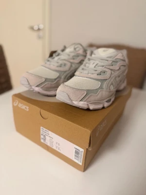 Asics GEL-NYC sneakers i ljusgrått - Säljer ett par Asics GEL-NYC sneakers i en clean mix av ljusgrått, vitt och beige. Skorna har meshpaneler, detaljer i mocka och syntet samt en chunky sula med Ortholite komfort. Perfekta för dig som gillar sportig och trendig stil.