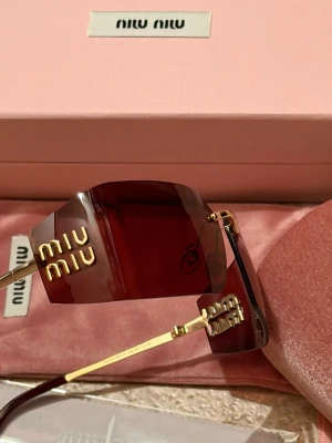 Röda solglasögon från Miu Miu - Snygga solglasögon från Miu Miu med allt som finns i bilder. Ni vet varför är billig!!.