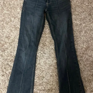 Bootcut jeans från Bershka, mörkblå - Snygga mörkblå bootcut jeans från Bershka i storlek 32. Klassisk femficksmodell med låg midja och markerade sömmar framtill. Jeansen är tillverkade i jeansmaterial och har en stilren look som passar till sneakers eller boots.