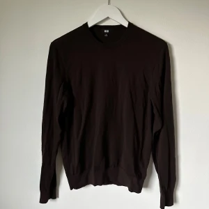 Mörkbrun tröja från Uniqlo, S - Snygg mörkbrun tröja från Uniqlo i storlek S. Tröjan har rund hals, långärmad design och är tillverkad i mjuk bomull. Enkel och stilren modell som passar perfekt till jeans eller chinos. Ribbstickade muddar vid ärmslut och nederkant för extra komfort. 5J5