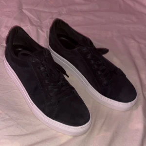 Svarta sneakers med vit sula - Snygga svarta Vagabond sneakers i mocka med klassisk vit platt sula. Skorna har rund tå, snörning och en stilren design som passar till det mesta. Perfekta för dig som gillar en clean och enkel look. 