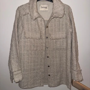 Beige overshirt från Levate Room - Säljer en beige overshirt från Levate Room med grov textur och fransade kanter. Skjortan har två stora bröstfickor, knappar framtill och lång ärm. Perfekt för lager-på-lager och har en chill oversized passform.
