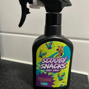 Scooby Snacks Body Spray 200ml - Limited edition Scooby-Doo x Lush body spray med färgglad design. Innehåller ekologisk alkohol, vatten, parfym, vaniljextrakt, glycerin, och eteriska oljor. Volym: 200ml. Vegansk och självkonserverande.