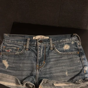 Blå jeansshorts från Hollister - Säljer ett par snygga blå jeansshorts från Hollister med slitna detaljer och uppvikta kanter. Klassisk femficksmodell med knapp och dragkedja framtill. Skit snygga men passar tyvärr inte mig🥰