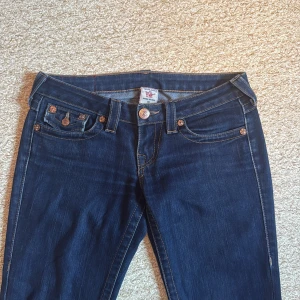 True Religion jeans - Snygga mörkblå jeans från True Religion med klassiska kontrastsömmar och ikonisk fickdesign bak. Modellen har bootcut-ben och låg midja. Dessa jeans är omsydda till bootcut så därav det låga priset (Se bild 4 & 5)💕Annars i bra skick. Pris går att diskuteras☺️