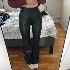 Svarta bootcut byxor i läder  - Nästan helt oanvända byxor då de är för stora för mig. (Ser ut som de är trasiga på höger knä men de är bara skrynkliga då de legat i garderoben länge). Det är ett fodrat material på insidan av byxorna så de blir varmt och skönt nu på vintern. 