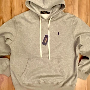 🩶 Grå Polo Ralph Lauren Hoodie -  Klassisk grå hoodie från Polo Ralph Lauren – ny med taggar. Mjuk, bekväm och passar perfekt till vardags eller chill. Diskret broderad logga på bröstet.  💰 Pris: 849 📦 Fraktas snabbt 