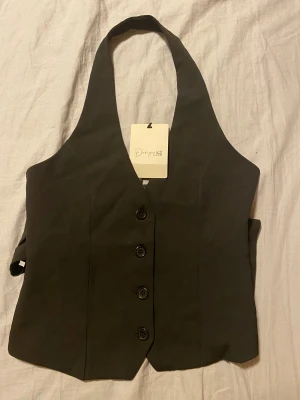 Svart omlott väst från Design Si - Säljer en svart väst från Design by si, den är i stork xs/s och har aldrig användts samt prislapp kvar❣️priset går å diskutera🫶🏻