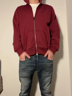 Mörkröd zip kofta med fickor från Colmar  - Snygg mörkröd kofta med hel dragkedja framtill och två stora fickor. Jackan har en hög krage och ett litet märke på vänster ärm. Tillverkad i mjukt bomullsmaterial, perfekt för chill dagar. Passformen är loose och ärmarna är långärmade.