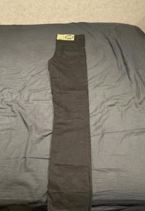 Svarta skinny jeans från Cheap Monday - Säljer ett par svarta skinny jeans från Cheap Monday med klassisk dödskalle-patch bak och metallknapp framtill. Jeansen har fem fickor och är tillverkade i stretchig bomull för en tajt passform. Perfekt för dig som gillar en clean och stilren look.