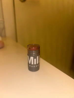 Milk Makeup Lip + Cheek Stick - Milk Makeup Lip + Cheek Stick i färgen werk. Multifunktionell krämprodukt som funkar både som rouge och läppfärg. Kommer i en smidig grå plastförpackning med transparent lock. Enkel att applicera direkt på huden för en naturlig glow. Använd 1 gång.🫰🏼