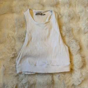 Vit ribbad linnetopp från 157 - Säljer en vit ribbad linnetopp från 157 i storlek XS/S. Toppen är ärmlös med breda axelband och har en croppad passform. Perfekt för en fräsch och enkel look, funkar lika bra till jeans som till shorts.