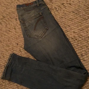 Ljus blåa dondups - Snygga blå jeans från Dondup, tillverkade i Italien. Jeansen har klassisk femficksdesign, raka ben och subtila slitningar för en avslappnad look. De är gjorda i mjuk bomullsdenim och har en stilren passform som funkar till många olika outfits.