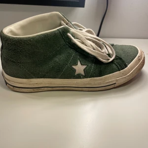 Converse One Star gröna mockasneakers - Gröna Converse One Star sneakers i mocka med vit stjärndetalj på sidan och vita snören. Klassisk retrostil med vit sula och märkning bak. Skorna har rund tå och platt sula, perfekt för dig som gillar streetwear och vill sticka ut.