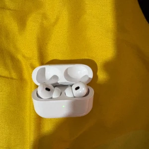 AirPods Pro 2 - Säljer ett par AirPods Pro 2 i mycket fint skick, komplett med originalförpackning och USB-C laddningskabel. Hörlurarna och laddningsetuiet är rena och utan synliga repor eller skador. Perfekt för dig som vill ha aktiv brusreducering och hög ljudkvalitet.