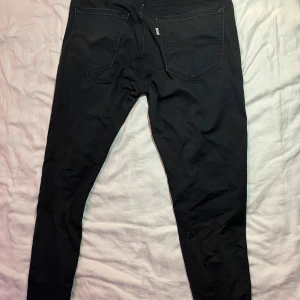 Svarta Levi's 512 jeans W32 L32 - Svarta Levi's 512 jeans med klassisk femficksdesign och smal passform. Jeansen har en snygg svart tvätt, läderpatch bak och diskret Levi's-tag på bakfickan. Perfekta för dig som gillar en modern och stilren look.