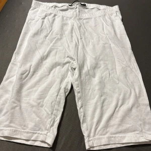 Vita långa shorts i bomull - Säljer ett par vita, enkla och långa shorts med resår i midjan. De är tillverkade i mjuk bomull och har en avslappnad passform som passar perfekt för varma dagar.