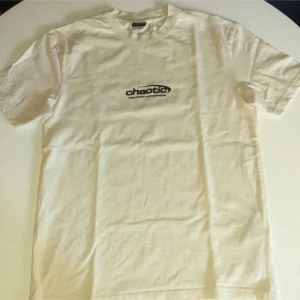 Vit t-shirt från FSBN med tryck - Snygg vit t-shirt från FSBN i relaxed fit med svart tryck 'chaotic' och text både fram och bak. Klassisk rund hals och korta ärmar. Perfekt för dig som gillar streetstyle och grafiska prints.