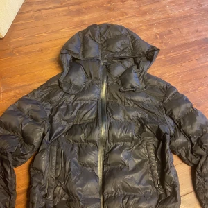 Svart pufferjacka från Zara XS - Säljer en svart pufferjacka från Zara i storlek XS. Jackan har huva, dragkedja framtill och två fickor med dragkedja. Perfekt för kalla dagar och har en riktigt snygg, puffig look.