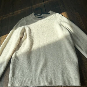 Beige stickad tröja från Vero Moda - Mysig beige stickad tröja från Vero Moda med rund halsringning och ribbade muddar. Perfekt för lager-på-lager och passar till allt. Enkel och stilren design med lång ärm och mjukt material.