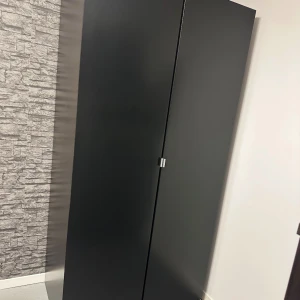 Svart garderob  - Svart garderobsskåp med två dörrar, en klädstång, en glashylla och två utdragbara nätkorgar. Skåpet ser modernt ut och är i gott skick utan skador eller slitage. Perfekt för förvaring av kläder och accessoarer i sovrum. Längd: 2m, bredd: 1m, djup: 50cm. Priset kan diskuteras vid snabb affär, hämtas på plats☺️