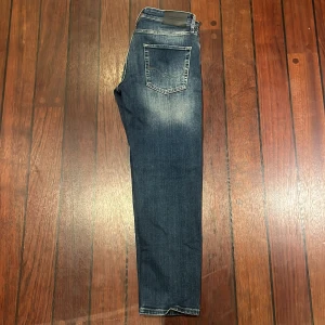 Helt nya Jack & Jones Tapered Mike jeans blå - Snygga blå jeans från Jack & Jones, modell Tapered Mike. Jeansen har en klassisk femficksdesign, gul kontrastsöm och lätt slitna partier framtill för en cool look. Tapered passform som smalnar av nedtill. Perfekta för dig som gillar stilrena och bekväma jeans.