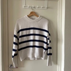 Vit och marinblå randig tröja Bik Bok - Vit stickad tröja från Bik Bok i storlek XS med breda marinblå ränder. Tröjan har rund hals med ribbad kant och långa ärmar. Materialet är 50% bomull och 50% akryl, vilket gör den mjuk och skön. Perfekt för dig som gillar klassisk och chill stil.