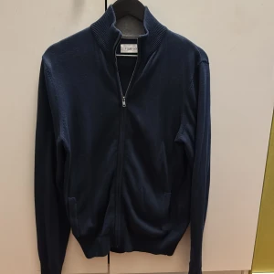 Marinblå kofta från Pier one - Snygg marinblå kofta från Pikone med dragkedja framtill och ribbad krage. Långärmad modell i mjukt material, perfekt för lager-på-lager. Enkel och stilren design som passar till det mesta.