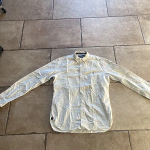 Vit skjorta Polo Ralph Lauren slim fit - Vit långärmad skjorta från Polo Ralph Lauren i slim fit-modell. Klassisk krage, knäppning framtill och broderad logga på bröstet. Tillverkad i mjuk bomull och har en stilren, tidlös look som passar till många outfits.