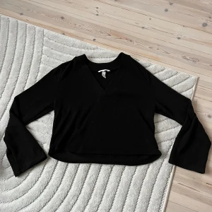 Svart croppad långärmad topp - Svart långärmad topp med v-ringning och croppad passform. 