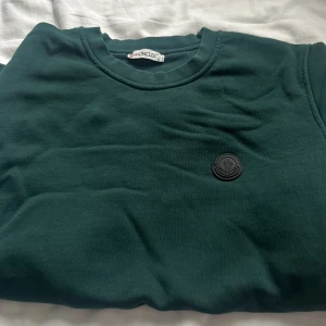 Moncler hoodie - De är en grön moncler tröja med en svart moncler logga, inga defekter alls, använd några gånger utav mig men inte tyckt om den särskilt mycket