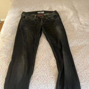 Svarta jeans från Demonna med kontrastsömmar - Snygga svarta jeans från Demonna med slitningar och markerade kontrastsömmar. Klassisk femficksmodell med unika bakfickor och läderpatch med logga. Jeansen har låg midja och raka ben, perfekt till sneakers eller boots.