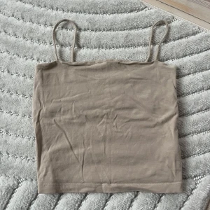 Beige linnetopp med smala axelband - Säljer en enkel och stilren beige linnetopp med smala axelband.