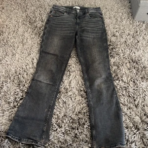 Gråa bootcut jeans Gina Tricot 158 - Snygga gråa jeans från Gina Tricot i storlek 158. Jeansen har en klassisk bootcut-modell med lätt utsvängda ben och femficksdesign. Materialet är jeans med en tvättad finish som ger en cool look. Perfekta för dig som gillar en avslappnad men trendig stil.