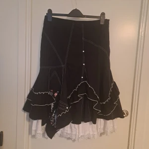 Svart kjol med spets - Svart kjol med underkjol och spets. Broderi och glitter på ena sidan.  Str 42, Märke Bonadea. 🩷