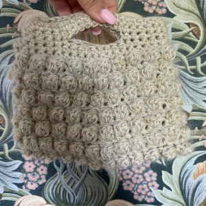 Handvirkad beige handväska med guld-glitter - Unik handvirkad handväska i beige med inslag av guldigt glitter. Med bland annat mohair. Väskan har ett bubbligt, stickat mönster och ett litet handtag upptill. Perfekt accessoar för dig som gillar personliga detaljer💕lägg gärna ett prisförslag, skriv om du har frågor(svarar snabbt) höjd 19cm, bredd 15cm