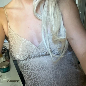 Beige leopardmönstrad linne - Säljer en superfin beige topp med leopardmönster och tunna axelband.  har v-ringning och är figurnära upptill. Materialet är glansigt och känns lyxigt, perfekt för dig som vill sticka ut lite extra.