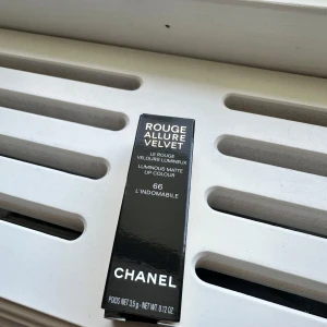 Chanel Rouge Allure Velvet 66 L'Indomabile - Chanel Rouge Allure Velvet i nyansen 66 L'Indomabile är ett lyxigt matt läppstift i en intensiv röd färg. Hylsan är elegant svart och guld med klassisk Chanel-logga. Läppstiftet har sammetslen finish och ger en djup, hållbar färg med lyxig känsla.